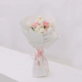 Elegant bouquet of pink tulips, white roses, and daisies wrapped in white paper