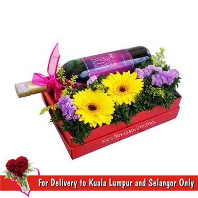 Red wine bottle gift box with yellow gerbera daisies and purple flowers arrangement
