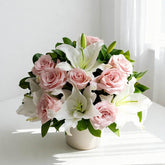 Elegant pink roses and white lilies floral arrangement in a white vase on a table