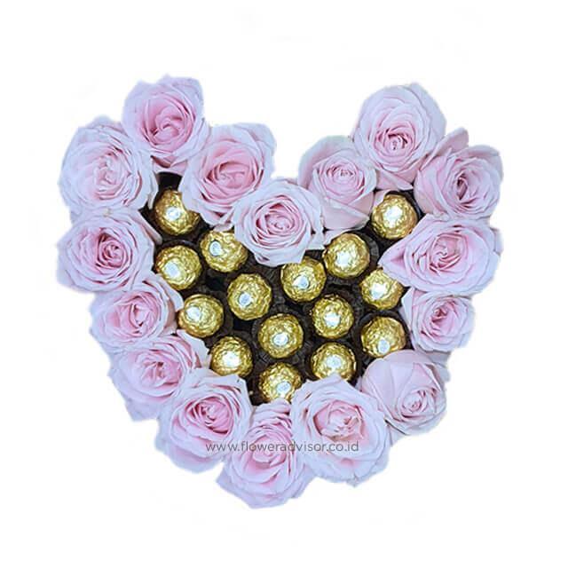 Heart-shaped arrangement of pink roses and gold-wrapped chocolates, ideal for gifts.