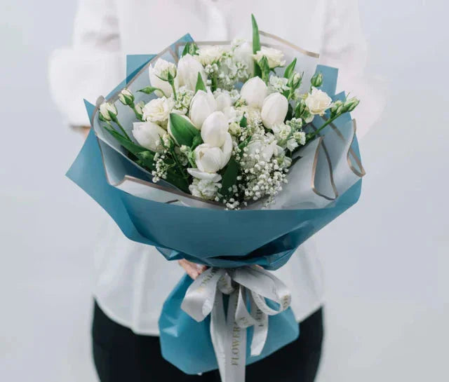 Elegant white tulip and rose bouquet wrapped in blue, ideal for sympathy or flower delivery