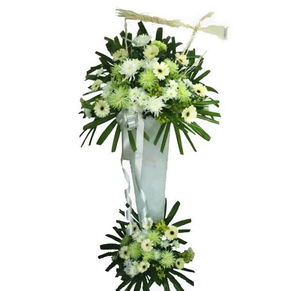Tall white funeral flower stand with white and pale green chrysanthemums and gerberas, decorated with green leaves