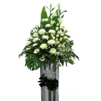 Elegant floral arrangement of white roses and chrysanthemums with green leaves in a tall silver vase