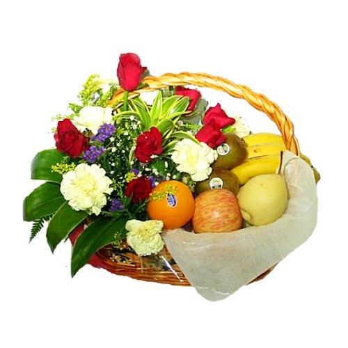 Fruit and flower gift basket with red roses, white carnations, bananas, apple, orange, and leafy greens