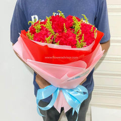 Person holding a bouquet of red carnations and yellow filler flowers wrapped in pink and red paper with blue ribbon, FlowerAdvisor Malaysia