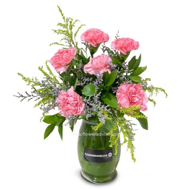 Pink carnations bouquet with green leaves and small purple flowers in a glass vase, fresh flower arrangement