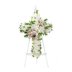 Elegant cross floral arrangement with white chrysanthemums, pink roses, lilies, and green leaves on a white stand
