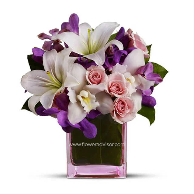 Elegant bouquet of white lilies, pink roses, and purple flowers in a pink glass vase for flower delivery