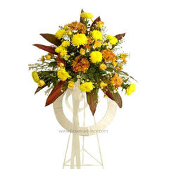 FlowerAdvisor Malaysia yellow and orange floral wreath with green leaves on white stand for flower delivery
