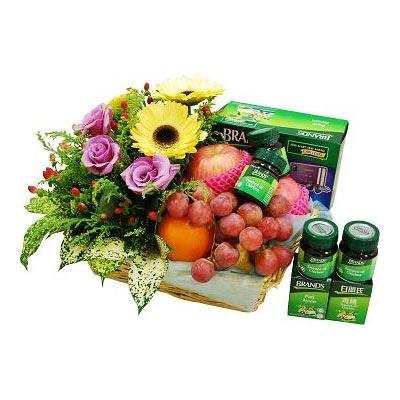 Fruit basket with grapes, orange, decorative flowers including sunflowers and purple roses, and health supplement jars