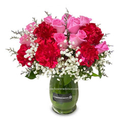 Fresh flower bouquet with pink roses, red carnations, and white baby's breath in glass vase