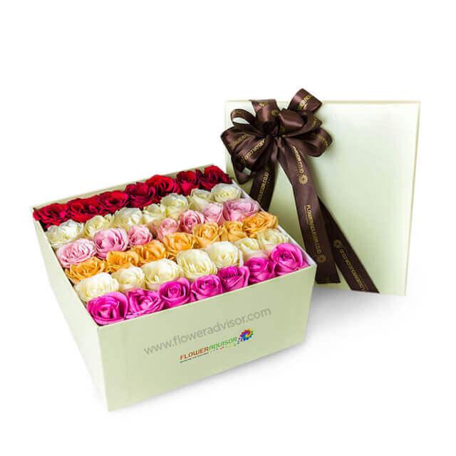 Elegant flower box with mixed red, white, pink, and peach roses tied with brown ribbon