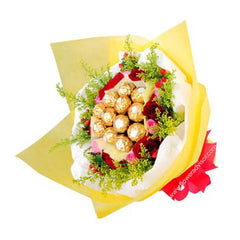 Bouquet with Ferrero Rocher chocolates, red roses, green foliage, wrapped in yellow and white paper with red ribbon