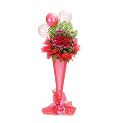 Tall standing floral arrangement with red and pink flowers, green foliage, and pink balloons wrapped in red mesh