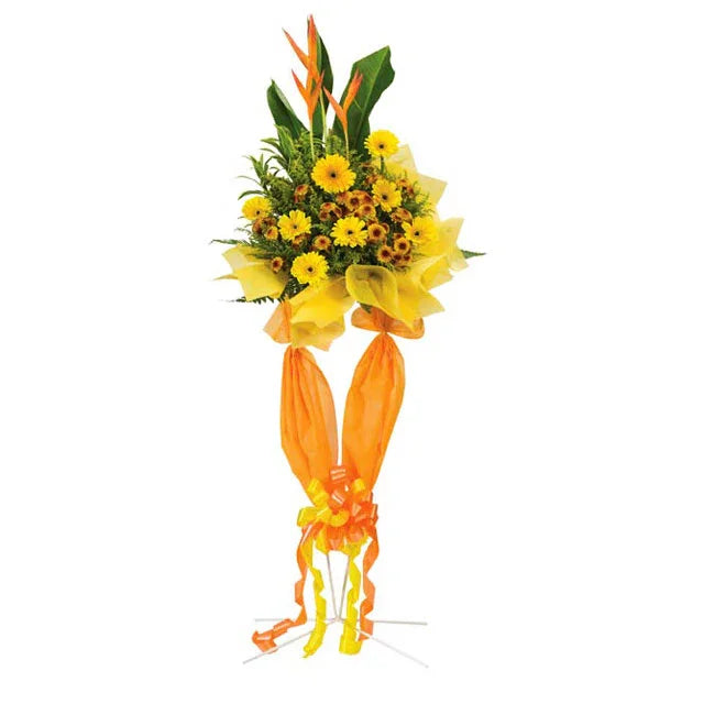 Yellow flower bouquet with gerbera daisies and tropical leaves wrapped in yellow and orange fabric