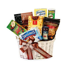 White woven gift basket with assorted snacks and treats including Swiss Miss, Famous Amos, and Mum's Bake cookies, decorated with a brown ribbon