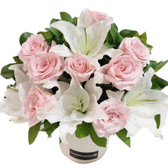 Bouquet of pale pink roses and white lilies in a round white flower box.