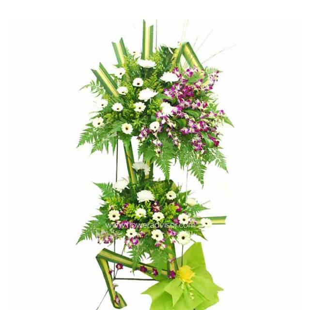 Two-tier floral arrangement with white and purple flowers, green foliage, and decorative leaves for flower delivery