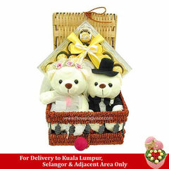 Wicker gift basket with two white teddy bears dressed as bride and groom and chocolates with yellow ribbon