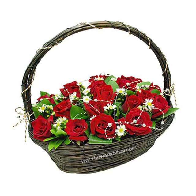 Basket of fresh red roses and white daisies with green leaves, elegant flower arrangement