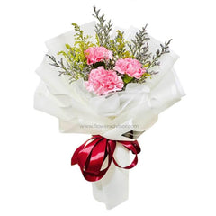 Elegant bouquet of pink carnations with greenery, wrapped in white paper and tied with a red ribbon