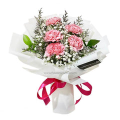 Bouquet of pink carnations and white fillers wrapped in white paper with pink ribbon, fresh flower delivery