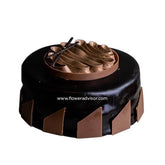 Round chocolate cake with glossy dark ganache, topped with chocolate curls and decorated with triangular chocolate pieces