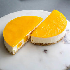 Two slices of mango cheesecake with creamy white filling and golden mango glaze on a white plate