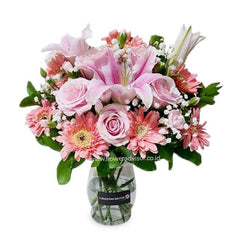 pink roses, lilies, and gerbera daisies bouquet in clear glass vase with green leaves flower arrangement