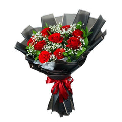 Bouquet of fresh red roses with white baby's breath wrapped in black paper and tied with a red ribbon
