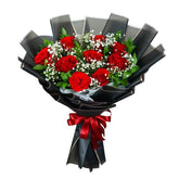 bouquet of fresh red roses with white baby's breath flowers wrapped in elegant black paper tied with a red ribbon