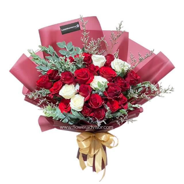 Bouquet of red and white roses with green leaves and pink wrapping, tied with gold ribbon