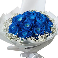 Bouquet of blue roses with white baby's breath flowers wrapped in white paper and tied with silver ribbon