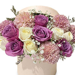 Elegant bouquet with purple roses, creamy white roses, pink chrysanthemums, and baby's breath in a soft beige vase