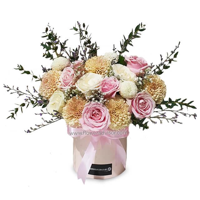 Elegant flower bouquet with pink roses, white roses, beige chrysanthemums, and greenery in a round box with pink ribbon