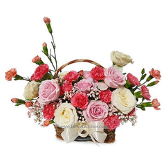 Wicker basket with pink and white roses, pink carnations, and baby's breath bouquet arrangement