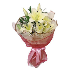 Elegant bouquet of white lilies with baby's breath wrapped in beige paper and red mesh tied with pink ribbon