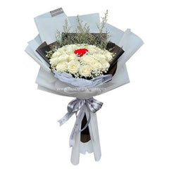 Elegant bouquet of white roses with a single red rose center, accented with greenery and white wrapping