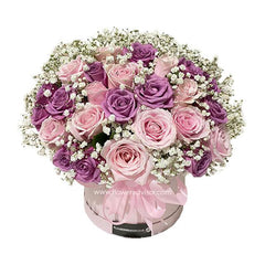 Elegant bouquet of pink and purple roses with white baby's breath in a round pink hatbox