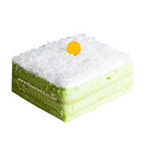 Square layered pandan cake with white coconut topping and yellow decoration on top