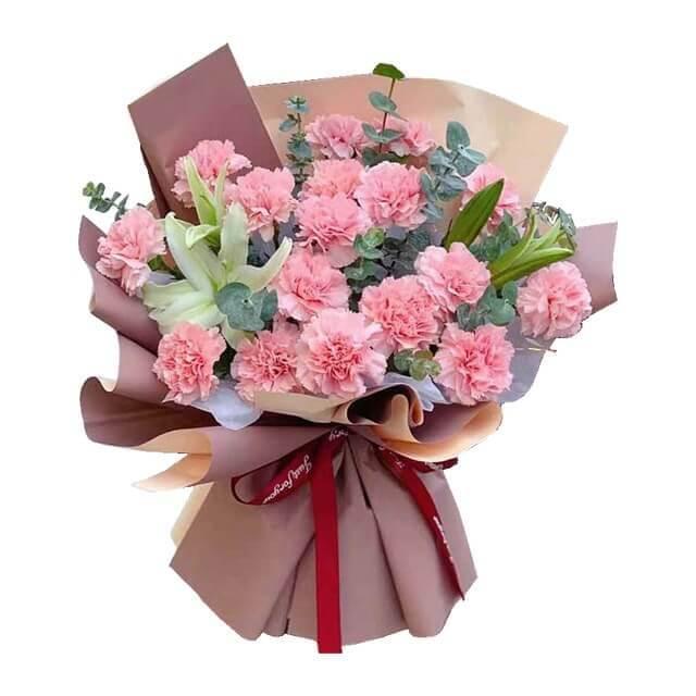 Fresh pink carnation bouquet with white lilies and greenery, wrapped in brown paper