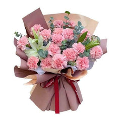 Fresh pink carnation bouquet with white lilies and greenery, wrapped in brown paper