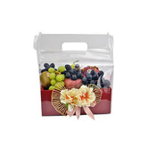 Fruit gift box with green and black grapes, kiwi, apples, decorated with flowers and pink ribbon