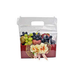 Fruit gift box with green and black grapes, kiwi, apples, decorated with flowers and pink ribbon