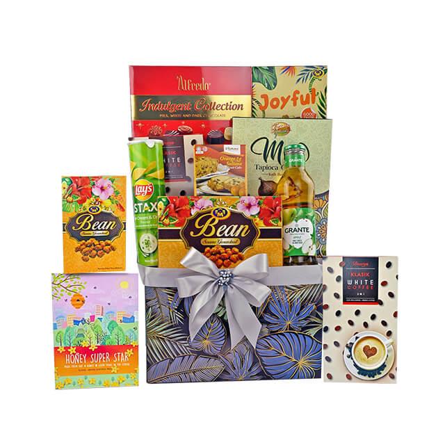 Elegant gift hamper with assorted snacks, cookies, chocolate, and beverages in decorative box with silver bow