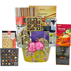 FlowerAdvisor Malaysia gift hamper with assorted chocolates, cookies, honey, crackers, and decorative pink flowers