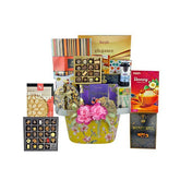 Luxury gift basket with assorted chocolates, honey, cookies, and gourmet treats decorated with pink flowers