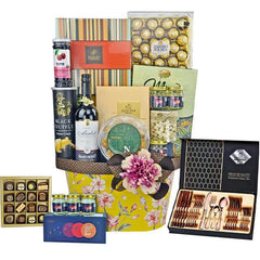 Luxury gift basket with wine, chocolates, cookies, nuts, and polished rose gold cutlery set in festive packaging