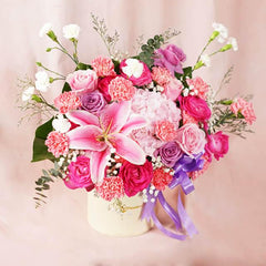 Elegant bouquet arrangement with pink lily, roses, carnations, and purple ribbon in white vase