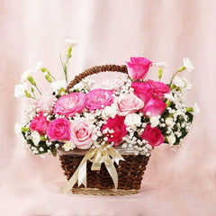 Basket of fresh pink and white roses with baby's breath flowers on soft pink background